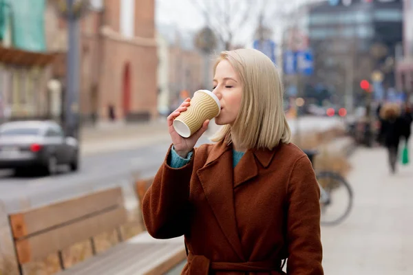 Krásná blondýnka s šálkem kávy na ulici města — Stock fotografie