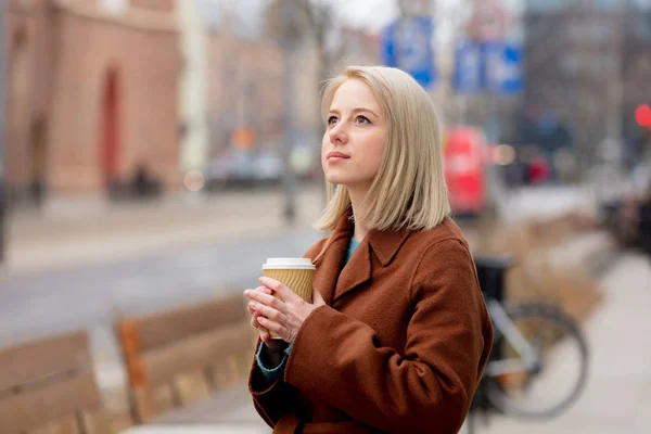 Şehir caddesinde elinde bir fincan kahve olan güzel sarışın kadın. — Stok fotoğraf