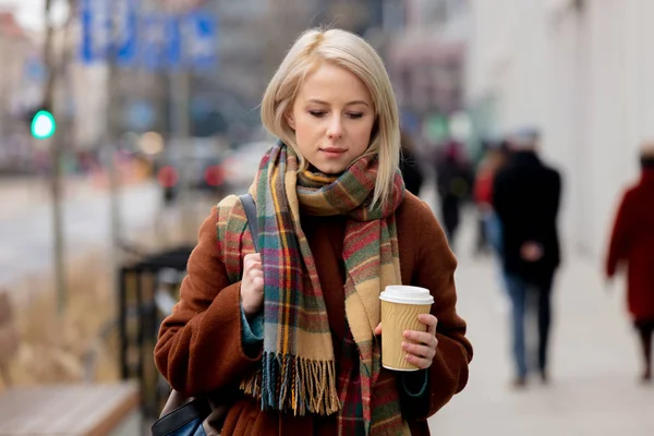 Piękna blondynka z filiżanką kawy na ulicy miasta — Zdjęcie stockowe