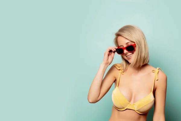 Piękna blondynka w żółtym bikini i okularach przeciwsłonecznych — Zdjęcie stockowe