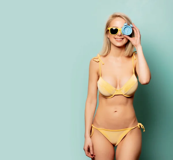 Schöne blonde Frau im Bikini mit Wecker — Stockfoto