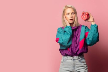 Beautiful blonde woman in 90s clothes with alarm clock