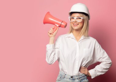 Beyaz gömlekli, gözlüklü ve kasklı hoparlörlü bir kadın. 