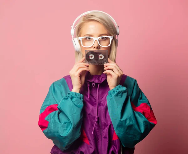 Mulher em roupas dos anos 90 com fones de ouvido e cassete de áudio — Fotografia de Stock