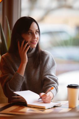 Not defteri ve cep telefonu olan esmer kadın. 