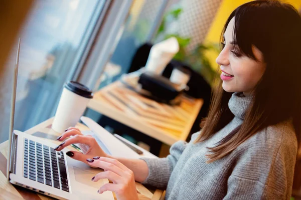 Brunette woman with laptop computer working in a cafe — 스톡 사진