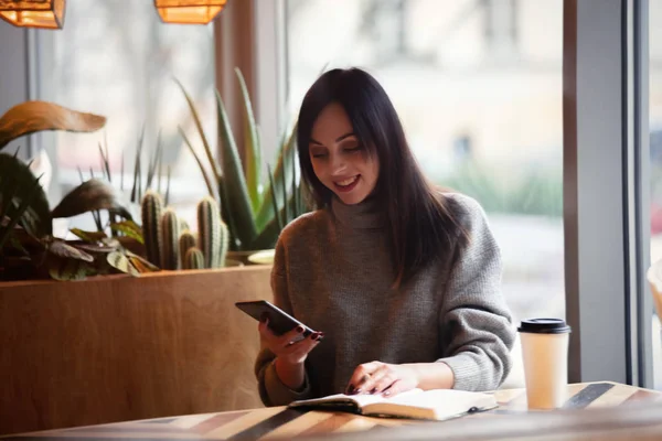 Donna bruna con notebook e telefono cellulare — Foto Stock