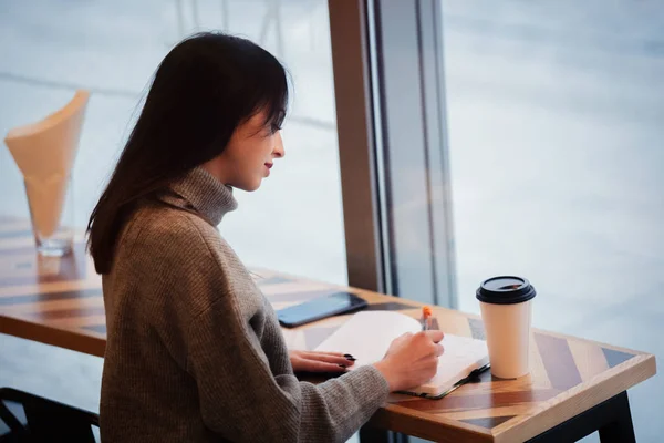 Bruna donna con notebook sta lavorando in un caffè — Foto Stock