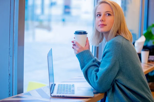Donna bionda bere caffè e lavorare con il computer portatile in un — Foto Stock