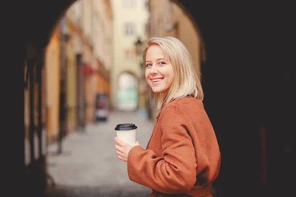 Blondýny žena s šálkem kávy ve starém městě — Stock fotografie