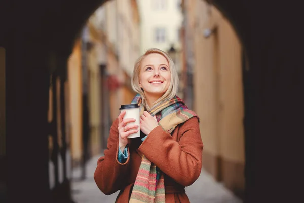 Blondýny žena s šálkem kávy ve starém městě — Stock fotografie