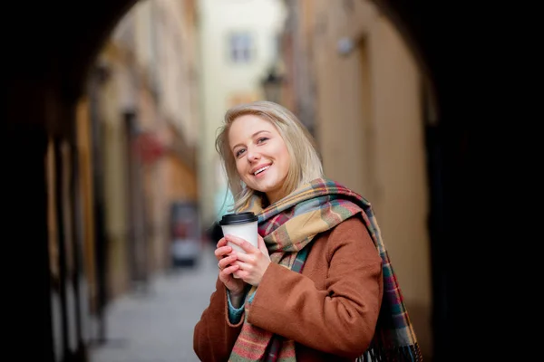 Blondýny žena s šálkem kávy ve starém městě — Stock fotografie