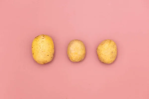 Three potatoes on pink background — Stock Photo, Image