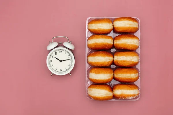 Traditional polish donuts in a box and alarm clock — Stock Photo, Image
