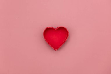 Pembe arka planda kalp şeklinde hediye kutusu