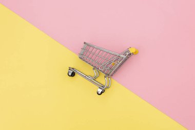 Pembe ve sarı arka planda metal alışveriş arabası. Görünümün üstünde
