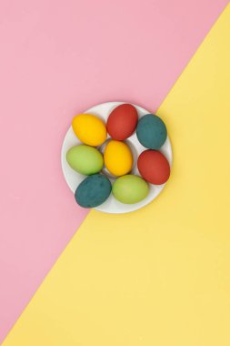 Sarı ve pembe arka planda renkli Paskalya yumurtaları