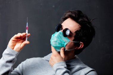 Koruyucu maskeli genç beyaz adam ve şırıngalı güneş gözlüğü.