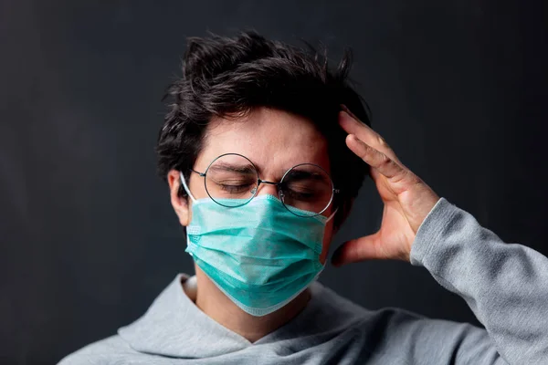 Joven hombre blanco en gafas y máscara protectora con dolor de cabeza —  Fotos de Stock