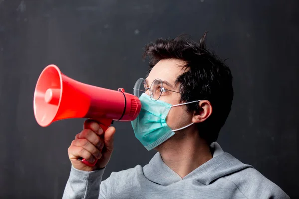 Young white man in glasses and protective mask with loudspeaker — Stock Photo, Image