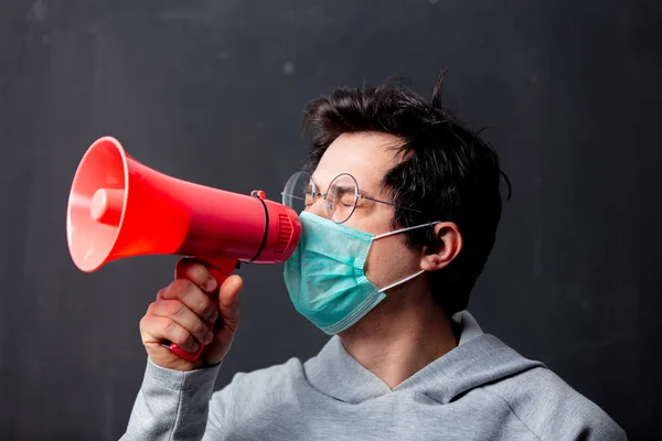 Young white man in glasses and protective mask with loudspeaker — Stock Photo, Image
