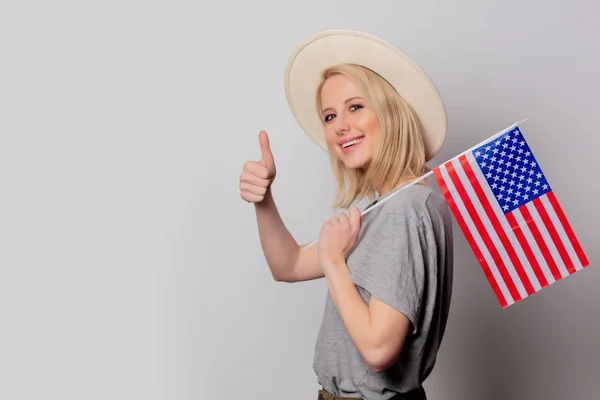 Mooie blonde vrouw in cowboy hoed met Usa vlag op witte rug — Stockfoto