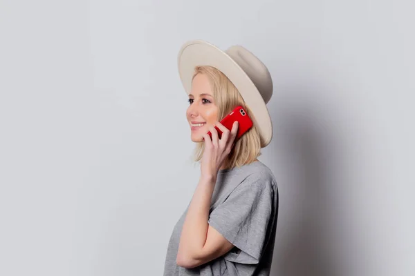 Chapéu de mulher loira usando telefone celular no fundo branco — Fotografia de Stock