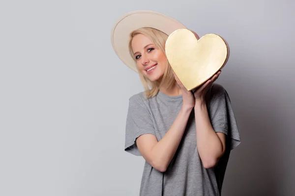 Piękna blondynka z pudełkiem w kształcie serca na białym tle — Zdjęcie stockowe