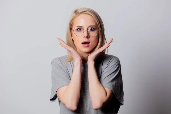 Ernste blonde Frau mit Brille auf weißem Hintergrund — Stockfoto