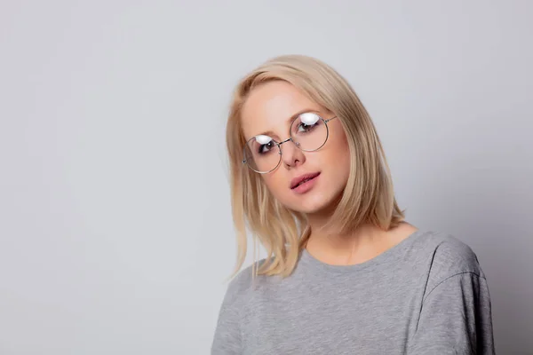 Grave blonde femme dans des lunettes sur fond blanc — Photo