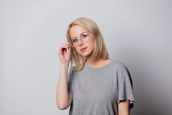 Grave blonde femme dans des lunettes sur fond blanc — Photo