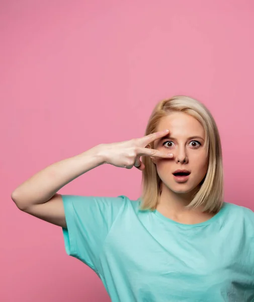 Förvånad kvinna visar fred gest på rosa bakgrund — Stockfoto