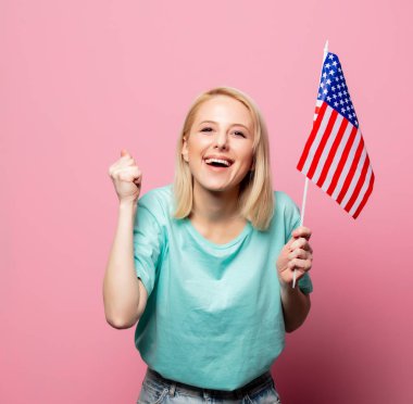 Pembe arka planda Usa bayrağı olan güzel sarışın kadın.
