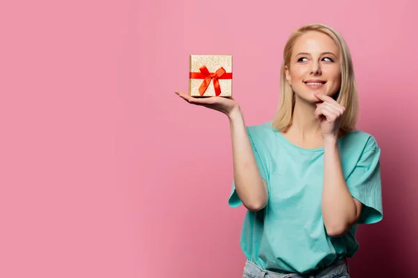 Beautiful smiling woman with gift box on pink background — Stock Photo, Image