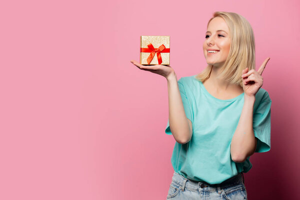 Beautiful smiling woman with gift box on pink background