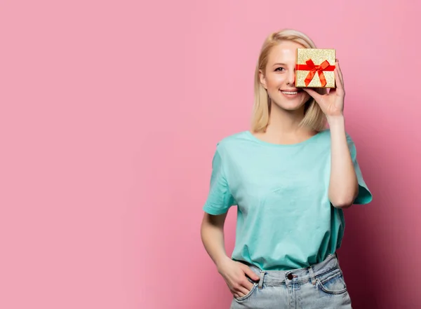 Mooie glimlachende vrouw met geschenkdoos op roze achtergrond — Stockfoto