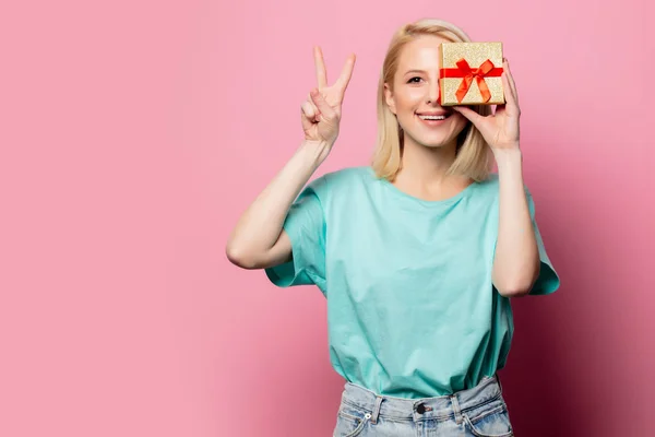 Belle femme souriante avec boîte cadeau sur fond rose — Photo