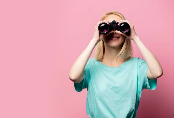 Krásná usmívající se žena s dalekohledem na růžovém pozadí — Stock fotografie
