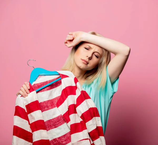 Hermosa mujer con camisa en una percha sobre fondo rosa — Foto de Stock