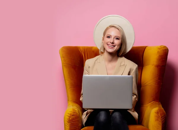 Piękna blondynka z laptopem siedzi w fotelu — Zdjęcie stockowe