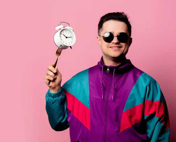 Style guy in 90s clothes with alarm clock on fork on pink backgr — 스톡 사진