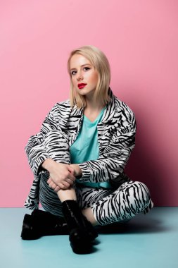 Style girl in zebra print clothes sitting on blue floor near a p