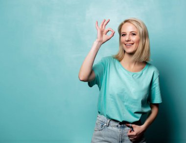 Beautiful blonde woman show OK gesture on blue background