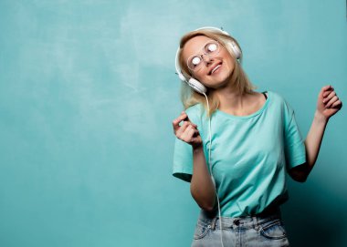 Style blonde woman in glasses with headphones is dancing