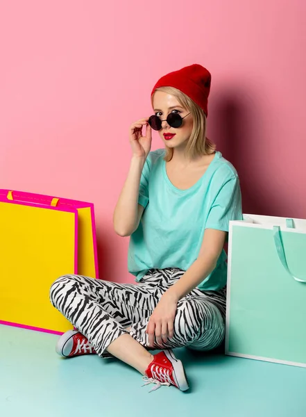 Style woman in sunglasses with shopping bags on pink background — Stockfoto