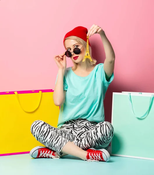 Stijl vrouw in zonnebril met boodschappentassen en kleine Eiffel t — Stockfoto