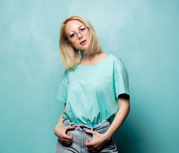 Styl blondýny žena v brýlích na modrém pozadí — Stock fotografie