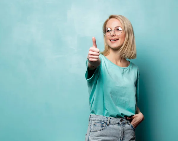 Stylowa blondynka w okularach pokazać Ok gest na niebieskim tle — Zdjęcie stockowe