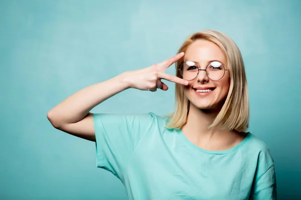 Estilo mulher loira em óculos mostrar gesto OK no fundo azul — Fotografia de Stock