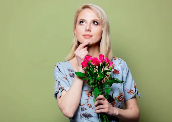 Vacker blond kvinna i klänning med rosor på grön bakgrund — Stockfoto